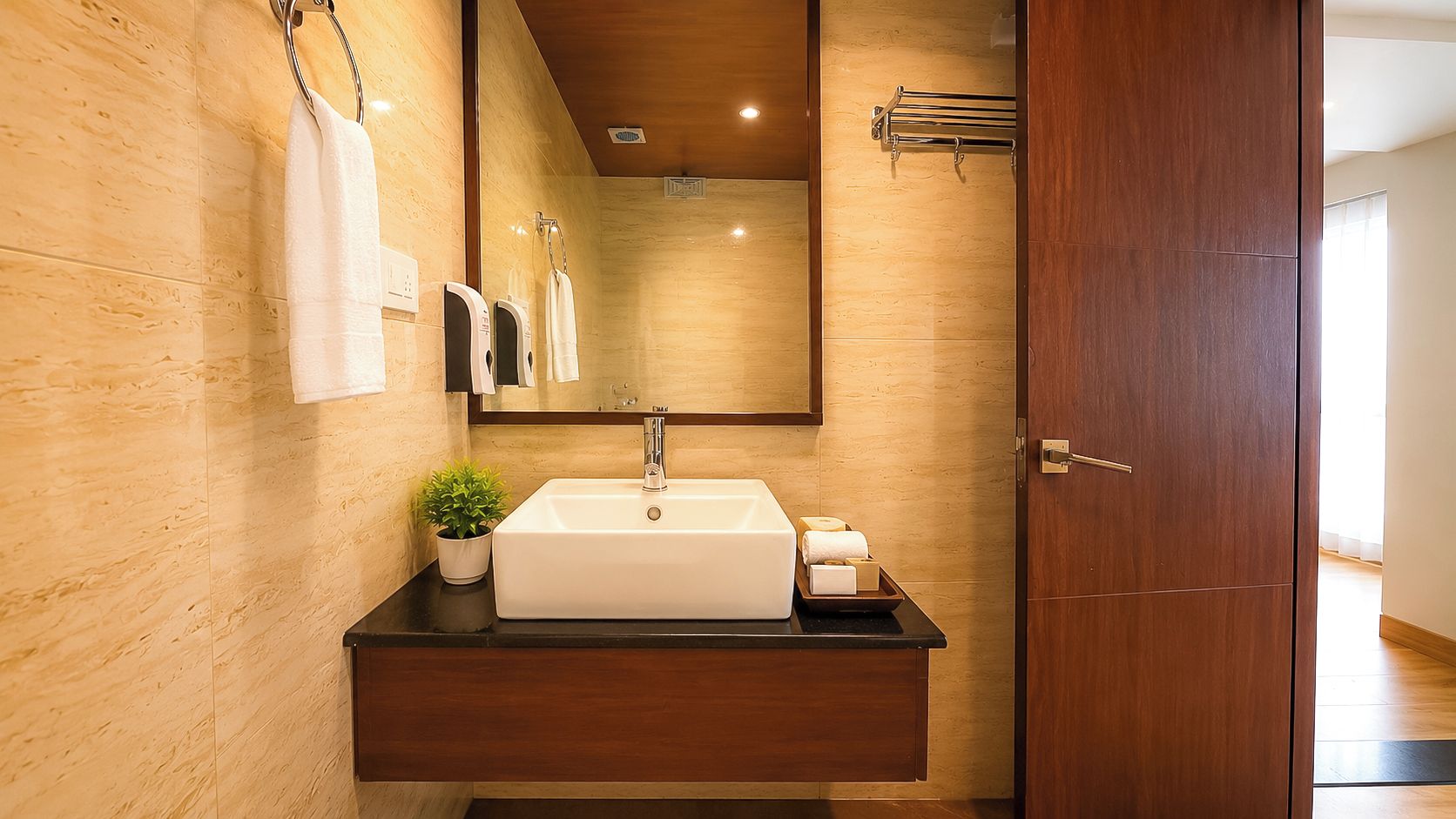 Une salle de bain avec un meuble-lavabo en bois, un évier, un miroir et une plante en pot.