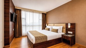 A hotel room with a large bed, a bedside table, a flat-screen TV, and a window with curtains. - Sumitel Vista 800m from Mall Road (Darjeeling)