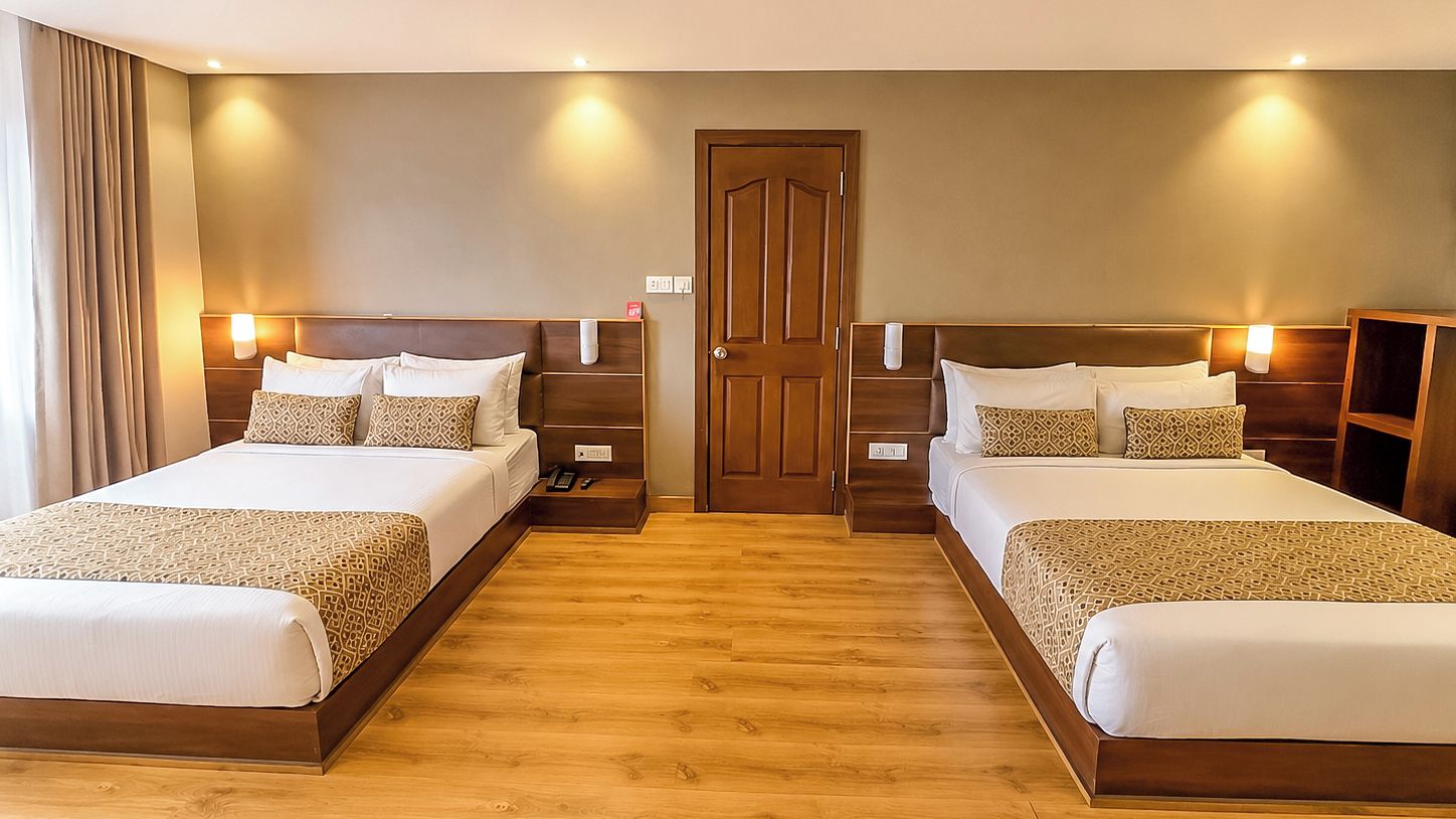 Habitación de hotel con dos camas, suelo de madera y lámparas de noche.