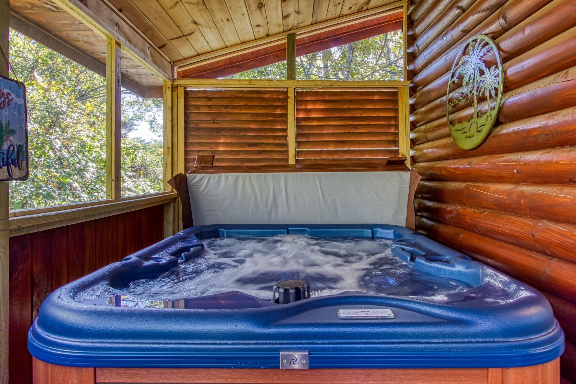 A hot tub in a wooden cabin with a view of trees through a window.