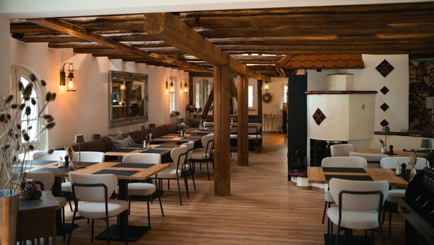 Un restaurant avec des poutres, des tables et des chaises en bois, disposées pour accueillir les clients.