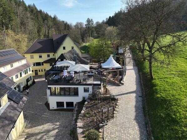 A courtyard with a modern building, traditional houses, and a white tent.