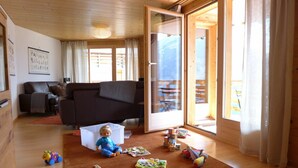 A cozy living room with a wooden floor, a brown sofa, and a child playing with toys.