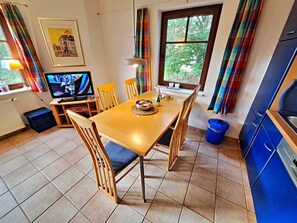 Ein Essbereich mit Holztisch, Stühlen und einem Fernseher.