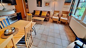 A compact living space with a kitchen, dining area, and seating area. - Wohnung 01 EG - Villa Adebar (Heringsdorf)