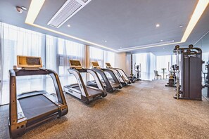 Una palestra con tapis roulant, cyclette e attrezzature per pesi.
