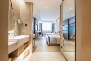 Una moderna camera d'albergo con bagno, una scrivania, un letto e un'ampia finestra.