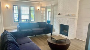 A modern living room with a sectional sofa, a round coffee table, and a fireplace. - Historic Main House Retreat (Orlando)