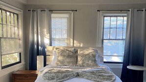 A bedroom with a bed, a ceiling fan, and two windows with blinds. - Historic Main House Retreat (Orlando)