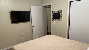 A bedroom with a bed, a television mounted on the wall, and two doors. - Spacious Orlando Home Near Theme Parks (Orlando)