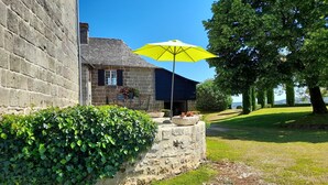 A stone building with a stone bench and a yellow umbrella. - Domaine Leyvinie, gite Syrah, 10 minutes from the Dordogne (Perpezac-le-Blanc)