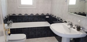 Een badkamer met een bad, toilet en wastafel.