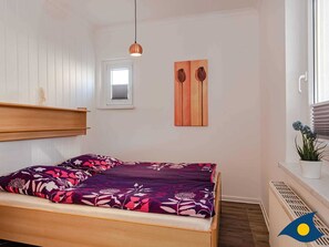 Quarto com cama, janela, radiador e uma obra de arte na parede.