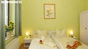 A room with two beds, a mirror, a framed picture on the wall, and a radiator.
