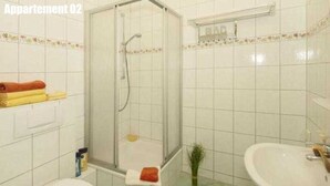 A bathroom with a shower, toilet, and sink.