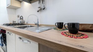 A modern kitchen with a stainless steel sink, a kettle, and a coffee maker. There are two black cups on coasters. - The House of Dreams of Serena in San Pietro (Rome)
