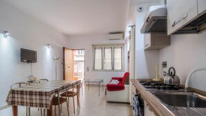 A modern kitchen with a dining area, a red chair, and a TV mounted on the wall. - The House of Dreams of Serena in San Pietro (Rome)