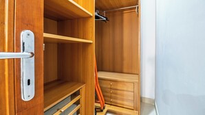 A wooden closet with open shelves, a hanging rod, and a ladder. - The House of Dreams of Serena in San Pietro (Rome)