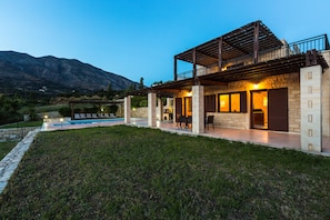 A modern villa with a pool, stone walls, and a balcony overlooking a mountainous landscape. - Villa Poseidon Lefkogis (Agios Vasileios)