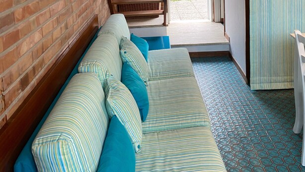 A cozy room with a sofa, a wooden shelf, and a view of the outside. - Domus Lido - 3 Bedrooms, 5 Persons, Wifi, Parking, air Conditioning (Comacchio)
