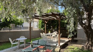 An outdoor patio area with a pergola, tables, chairs, and a small garden. - Room-beautiful Bedroom for 4 People in L (Thasos)