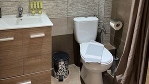 A modern bathroom with a white sink, wooden vanity, a toilet, and a shower curtain. - Room-beautiful Bedroom for 4 People in L (Thasos)