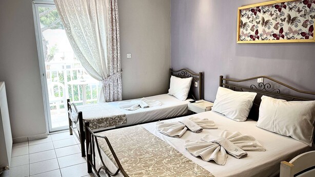 Une chambre d’hôtel avec deux lits, un balcon et une œuvre d’art à motifs floraux au mur.