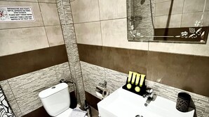 Une salle de bain avec des toilettes, un lavabo et un miroir. Un panneau avec du texte est accroché au mur.