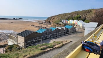 A row of beach huts with a view of the beach and ocean.