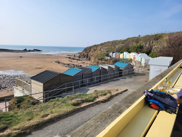 A row of beach huts with a view of the beach and ocean.