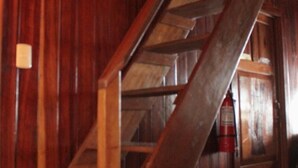 A wooden staircase in a rustic interior with a fire extinguisher visible. - Triple Room With sea and Mountain Views Perfecto for Couples (Drake Bay)