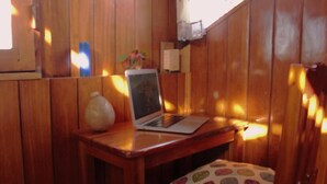 A wooden interior with a laptop on a small table, a vase, and a patterned cushion. - Triple Room With sea and Mountain Views Perfecto for Couples (Drake Bay)