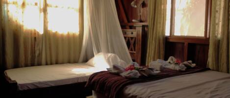 A bedroom with two beds, a nightstand, and a wooden dresser.