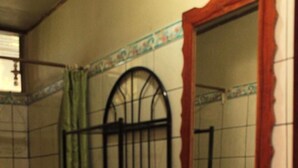 Un baño con inodoro, lavamanos con espejo y cortina de ducha.