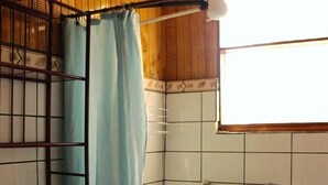 A bathroom with a toilet, a shower area with a blue curtain, and tiled walls.