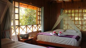 A wooden room with two beds, a ceiling fan, and windows with wooden frames. - Bungalow Casa Bosque, With Balcony and sea View (Drake Bay)