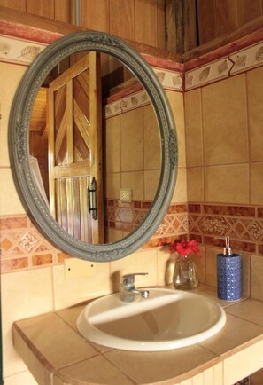 A bathroom with a round mirror, a sink, and a decorative tile backsplash.
