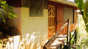A wooden house with a porch, a window, and a door. - Bungalow Casa Bosque, With Balcony and sea View (Drake Bay)
