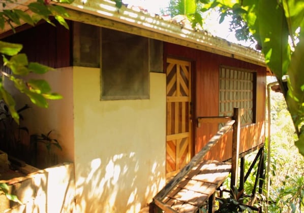 A wooden house with a porch, a window, and a door.