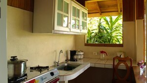 A kitchen with a gas stove, sink, and white cabinets. - Bungalow Casa Bosque, With Balcony and sea View (Drake Bay)
