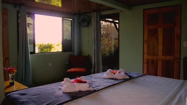 A room with a bed, a window, a chair, and a door.
