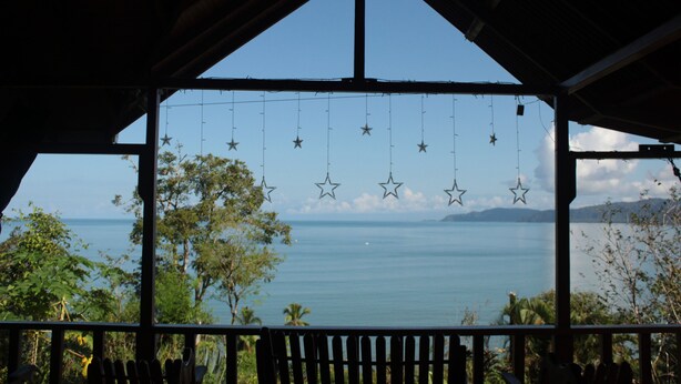 Un espacio al aire libre cubierto con vista al mar, decorado con estrellas y un banco de madera.