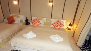Une chambre d’hôtel avec un grand lit, deux oreillers, une table de chevet avec une lampe et un tapis à motifs.