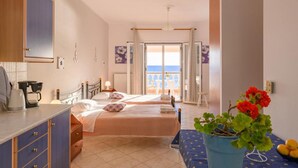 A hotel room with two beds, a kitchenette, a view of the sea, and a potted plant. - Beach House Tolis - Pelekas Beach (Corfu)