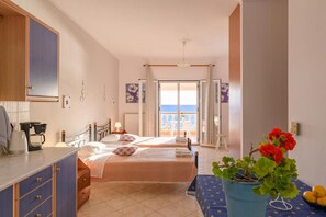 A hotel room with two beds, a kitchenette, a view of the sea, and a potted plant. - Beach House Tolis - Pelekas Beach (Corfu)