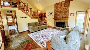 A spacious living room with a fireplace, a staircase, and a large rug.