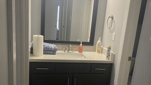 Ein Badezimmer mit einem großen Spiegel, zwei Waschbecken, dunklen Schränken und einer Toilette.