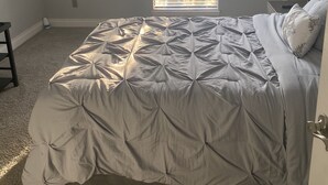 Ein Schlafzimmer mit einem Bett, einem Fenster, einem Deckenventilator und einem Nachttisch mit einer Lampe.