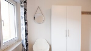 Ett sovrum med en säng, en vit garderob, en spegel och en stol.