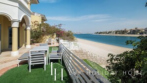 Ein luxuriöses Ferienhaus mit Terrasse mit Blick auf einen Strand, ausgestattet mit Gartenmöbeln und Meerblick.